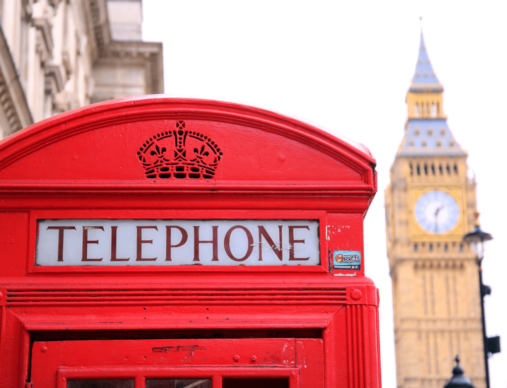 Red phone booth and Big Ben in blurred background symbolize a typical scene in England.